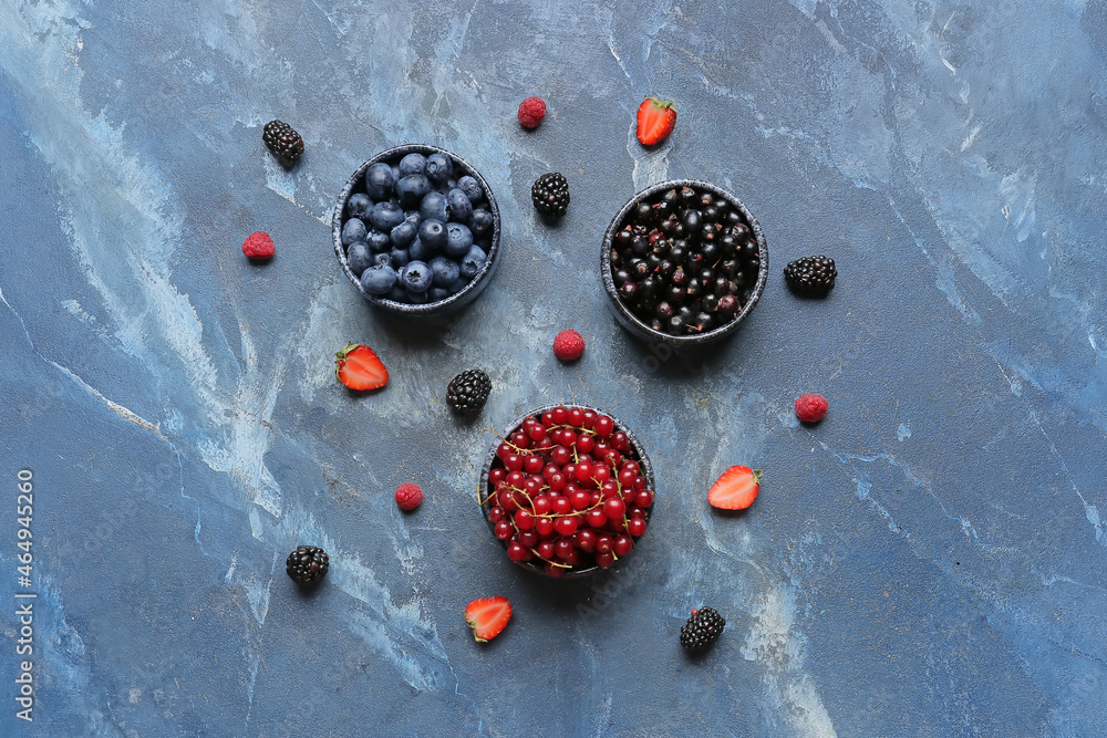 Bowls with different ripe berries on color background