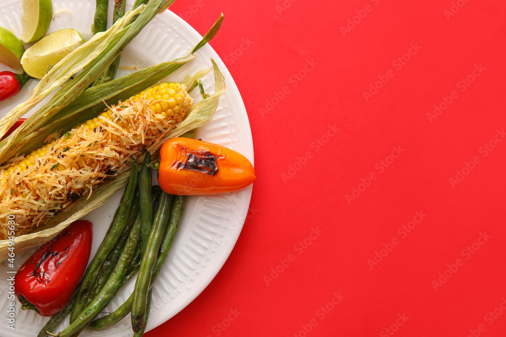 Plate with delicious Elote Mexican Street Corn and grilled vegetables on red background, closeup