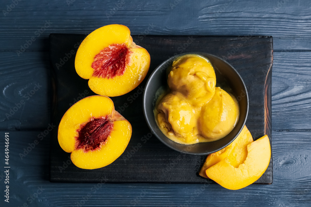 Bowl of tasty peach ice cream on black wooden background