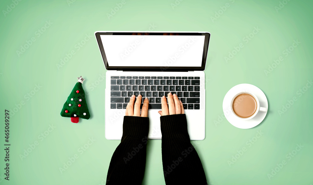 Person using a laptop computer with a Christmas tree cushion and a cup of coffee from above