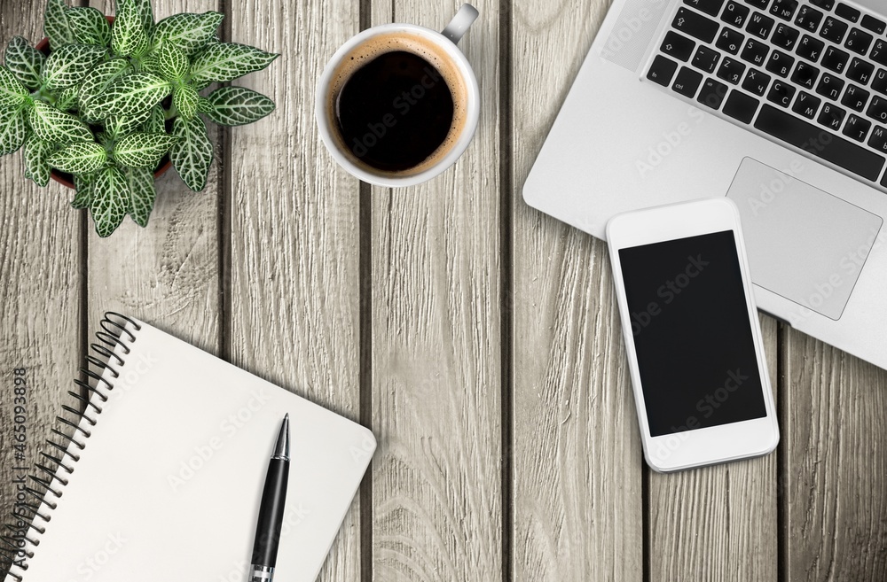 Modern office desk with laptop, coffee cup and pen on wood table.