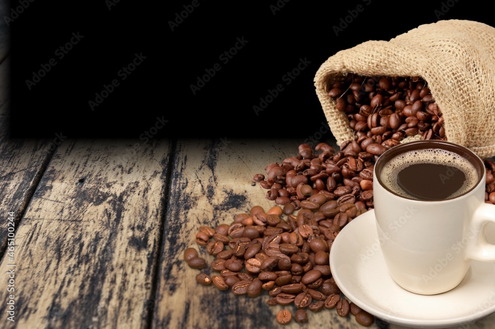 Hot coffee in a white coffee cup and many beans placed around