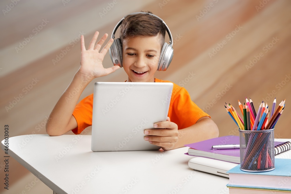 Little child using digital tablet and headphones studying at home,