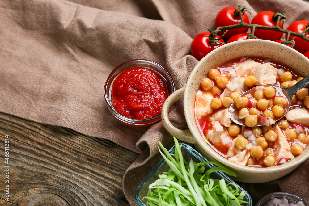 Bowl with delicious pozole soup and ingredients on wooden background