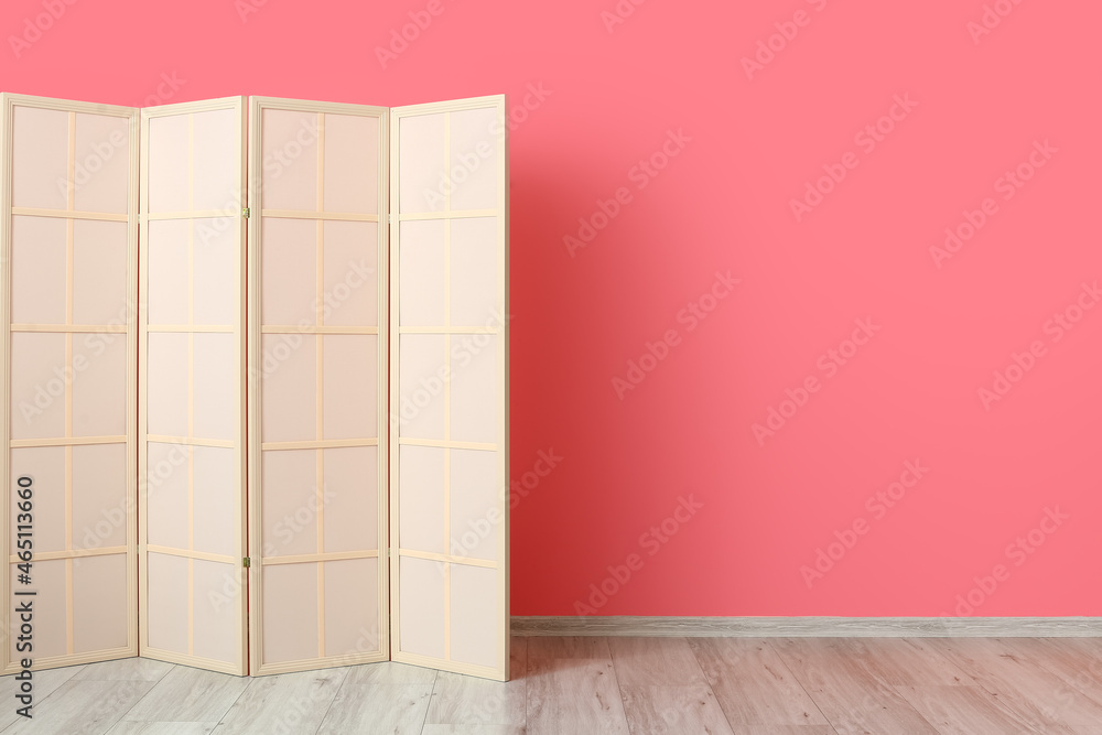 Light folding screen near pink wall