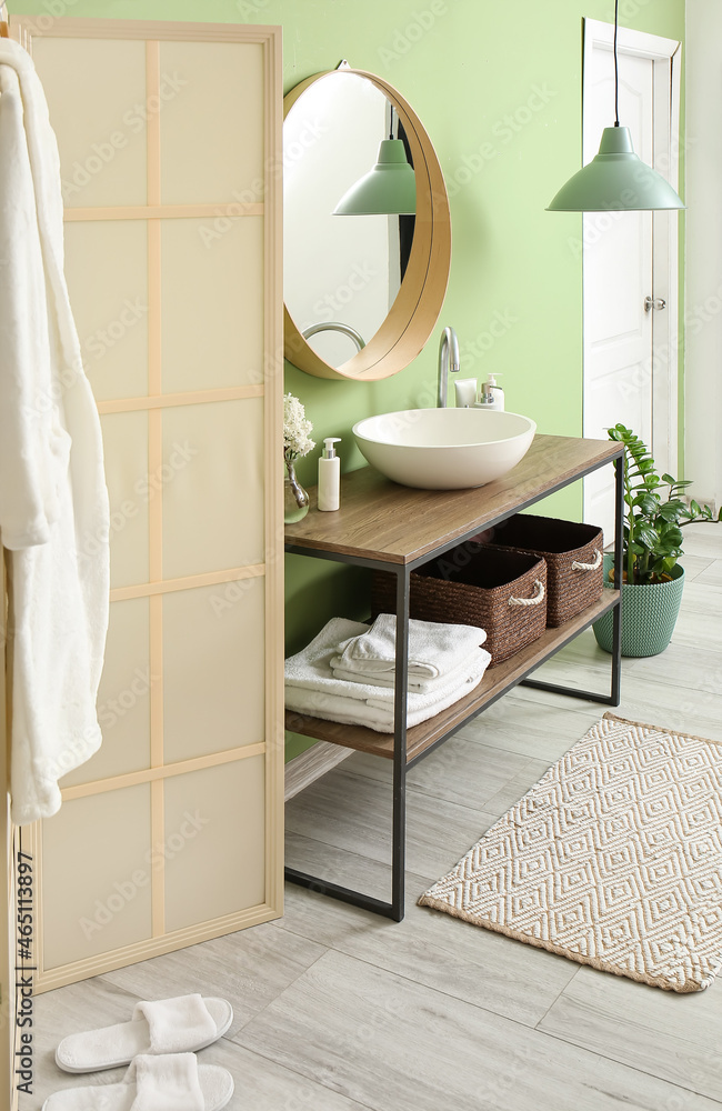 Table with sink and mirror near green wall