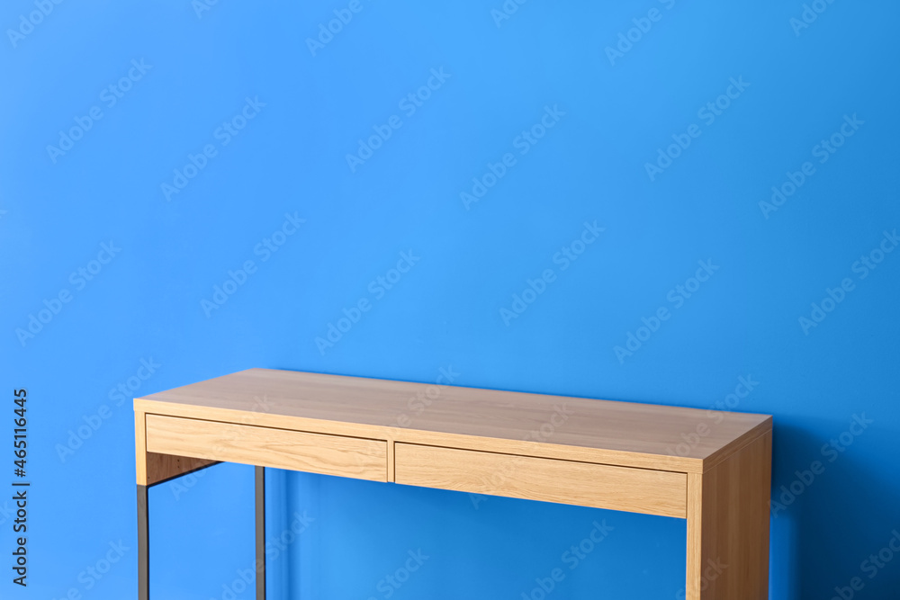 Wooden modern table near color wall