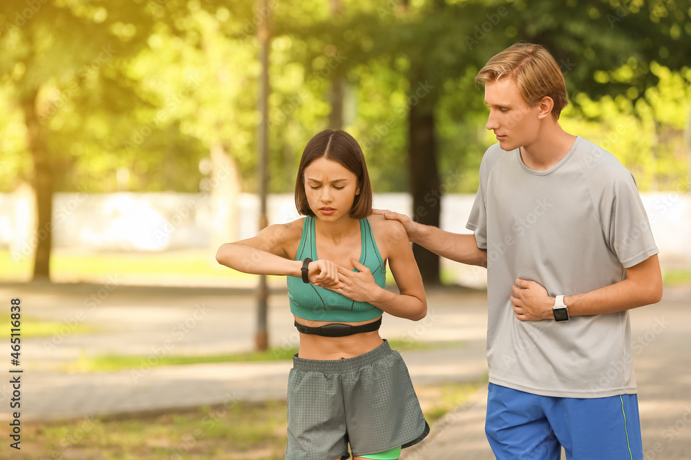 Sporty young couple checking pulse outdoors