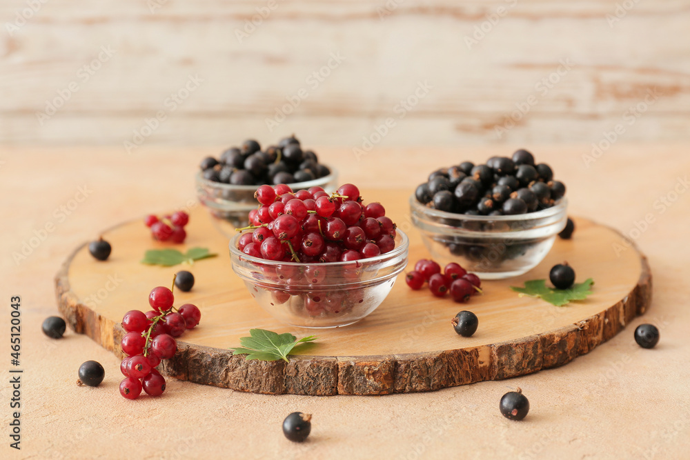 Bowls with tasty red and black currants on color background