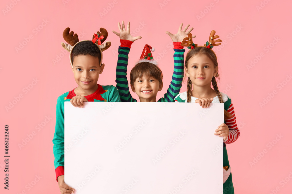 Little children dressed as elves with blank poster on pink background