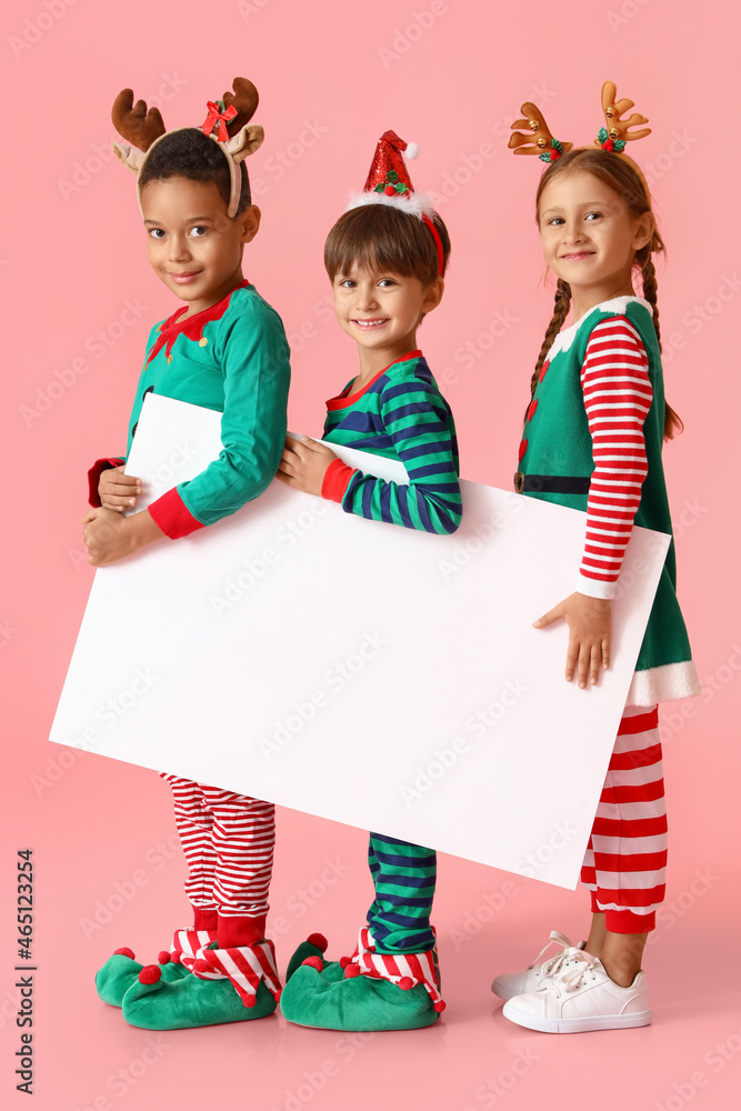 Little children dressed as elves with blank poster on pink background