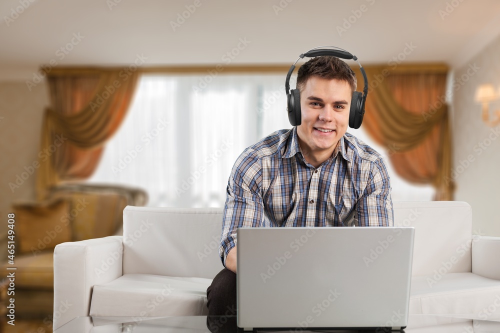 Cheerful teenager having video conference on laptop, wearing headset