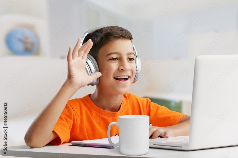 Smiling little child in headphones have a video call distant class using a laptop. Education concept