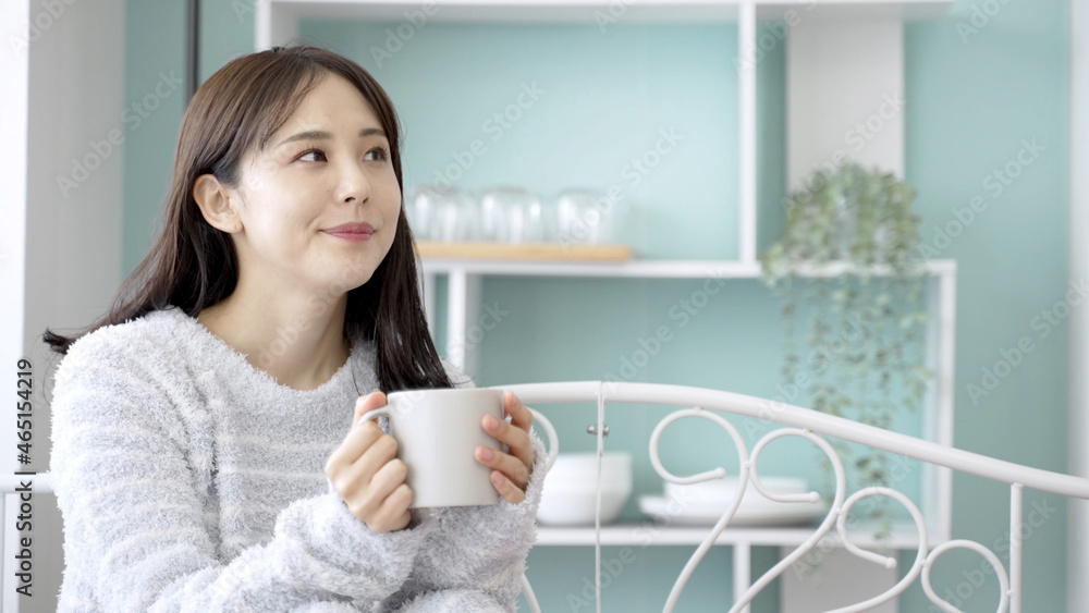 ベッドで飲み物を飲む女性