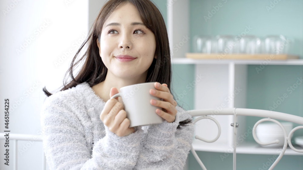 ベッドで飲み物を飲む女性