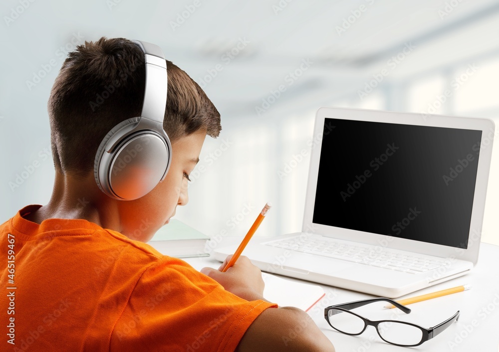 Young stylish school child studying homework during online lesson on a laptop