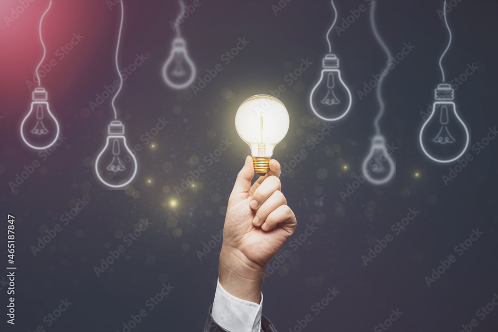 Businessman hand holding abstract light bulbs on dark background. Idea and innovation concept.