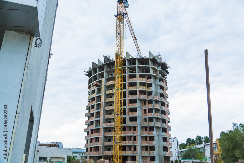 Large construction site including several cranes working on a building complex, with clear blue sky 