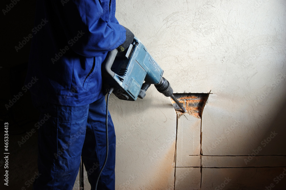 Builder with jackhammer breaking  wall