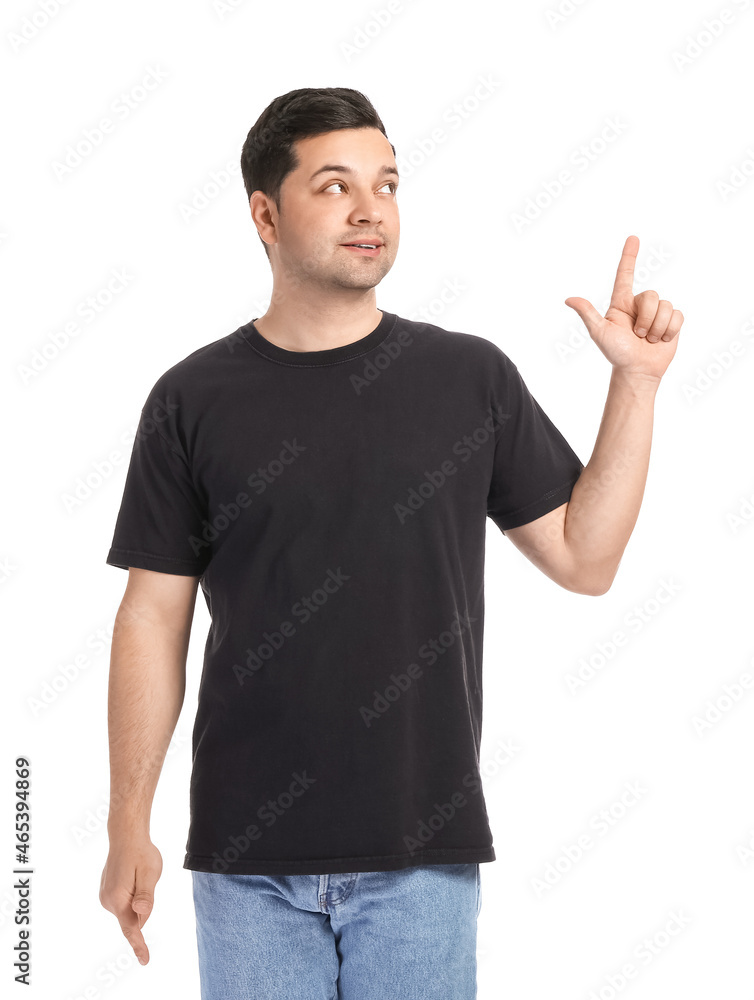 Handsome young man in stylish t-shirt pointing at something on white background