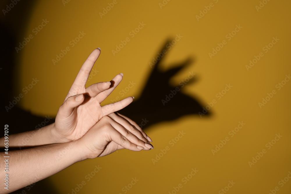 Woman making shadow moose with her hands on color background