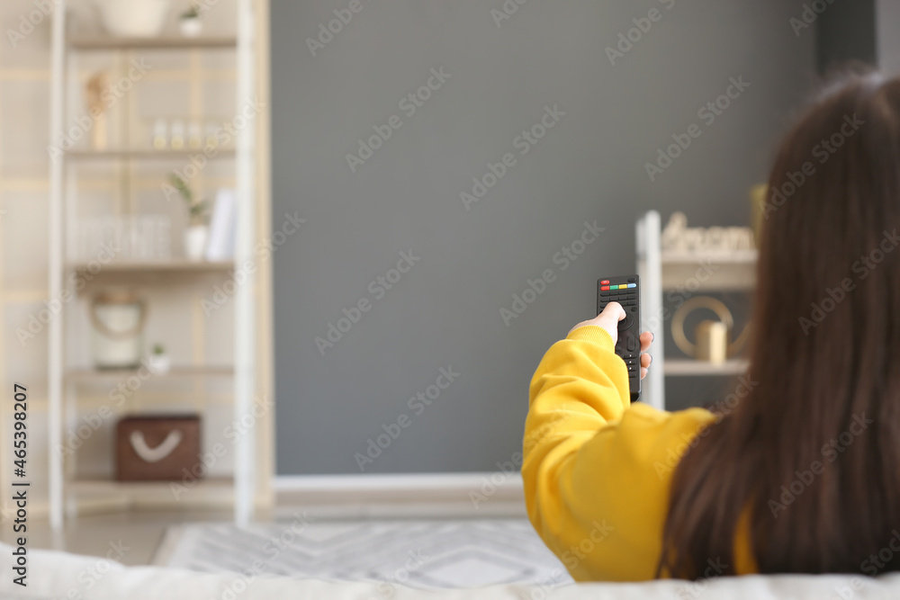 带遥控器的女人在家沙发上看电视