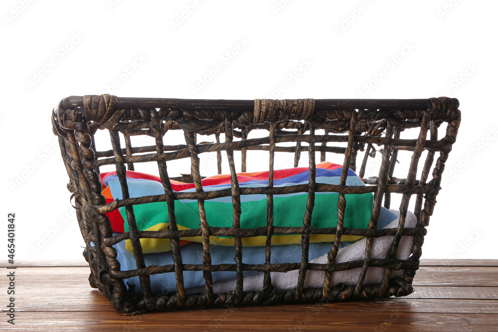 Wicker basket with clothes on wooden table against white background