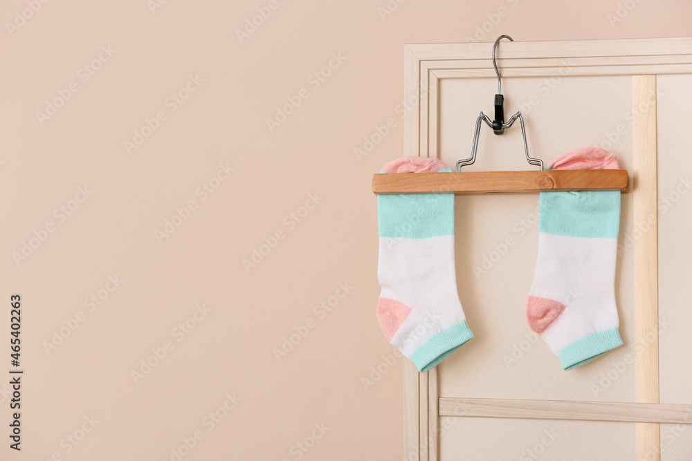 Hanger with stylish socks against color wall