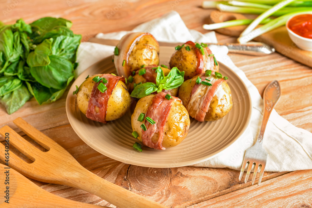 Plate of tasty baked potatoes with bacon on wooden background