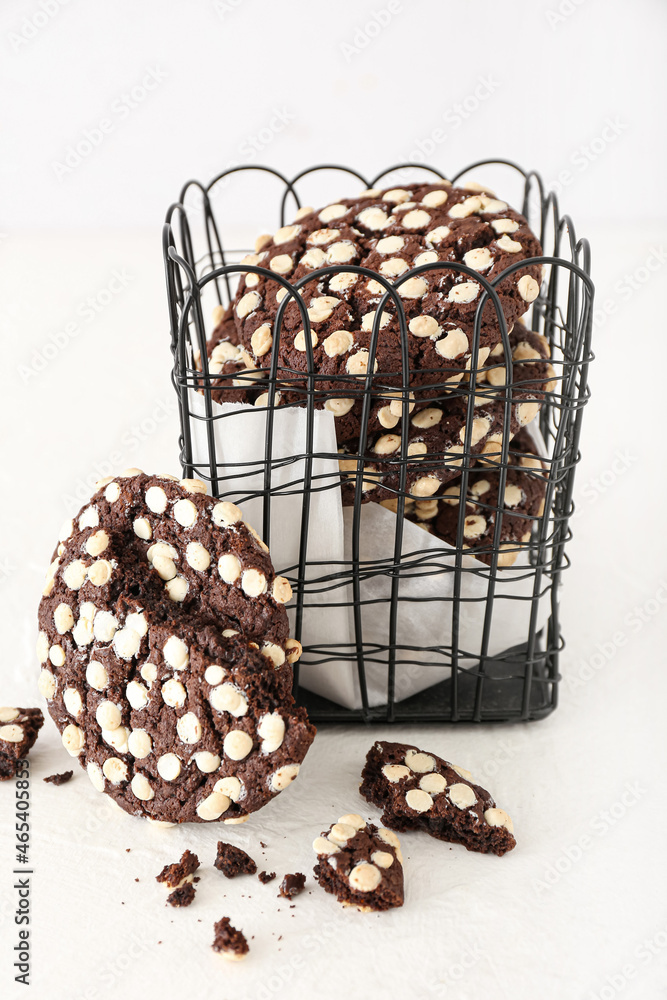 Metal basket with tasty chocolate cookies on white background