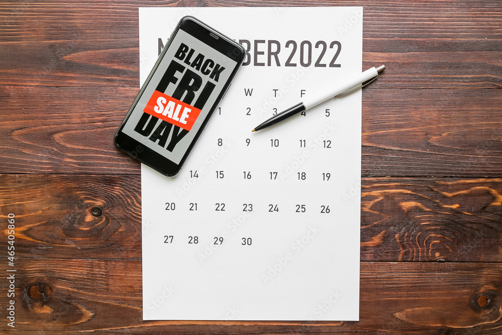 Mobile phone with text BLACK FRIDAY SALE, calendar and pen on dark wooden background