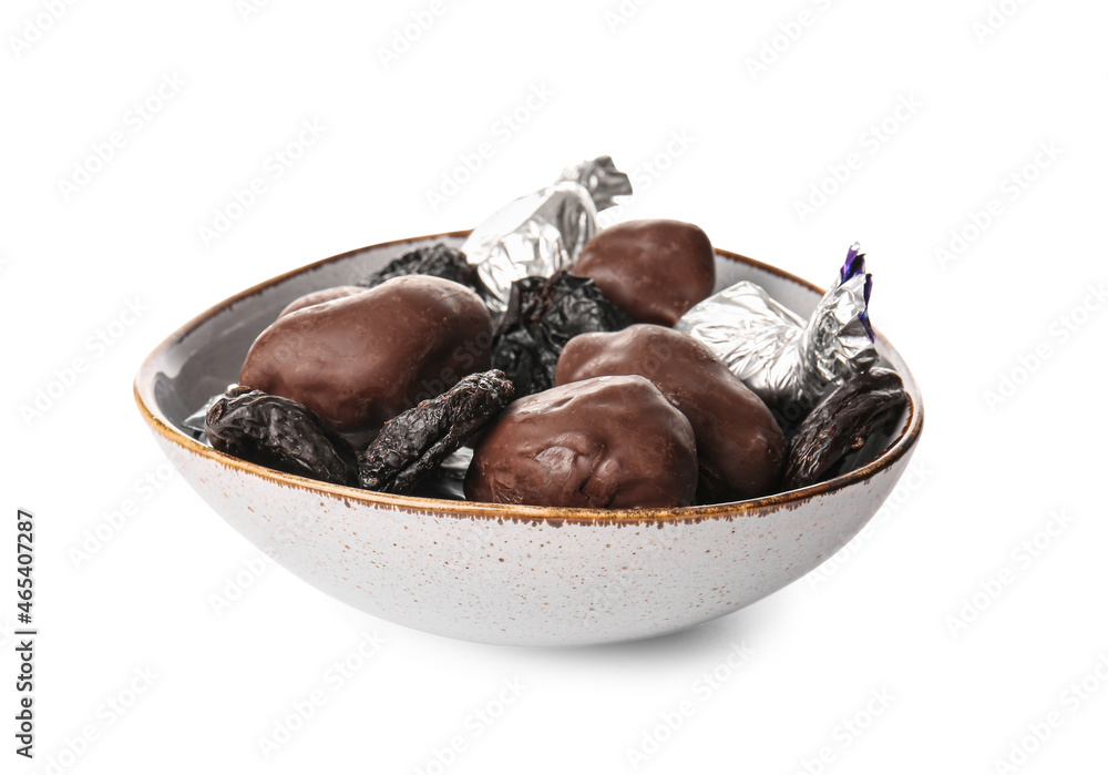 Bowl with delicious chocolate candies and prunes on white background