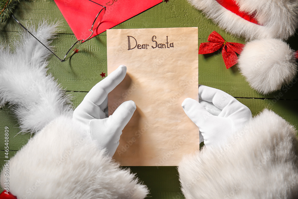 Hands of Santa Claus with empty letter at table