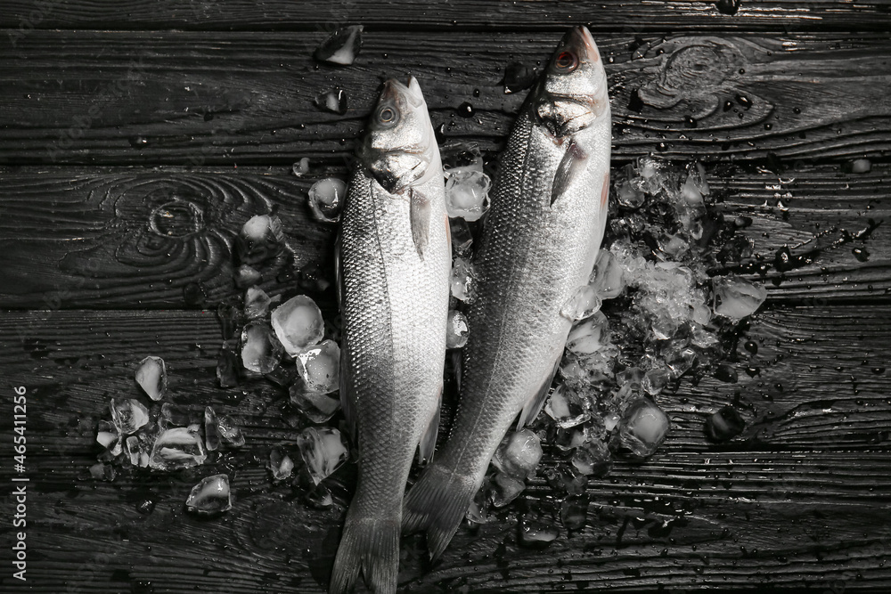 Fresh uncooked sea bass fish on black wooden background