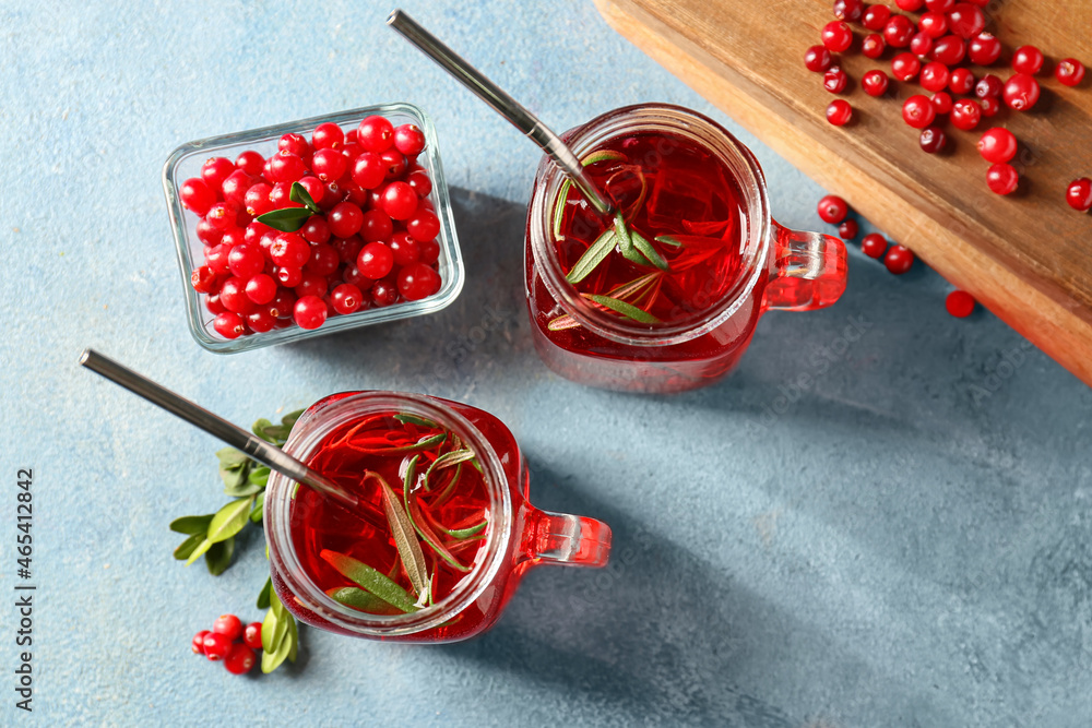 Mason jars of tasty lingonberry tea and berries on color background