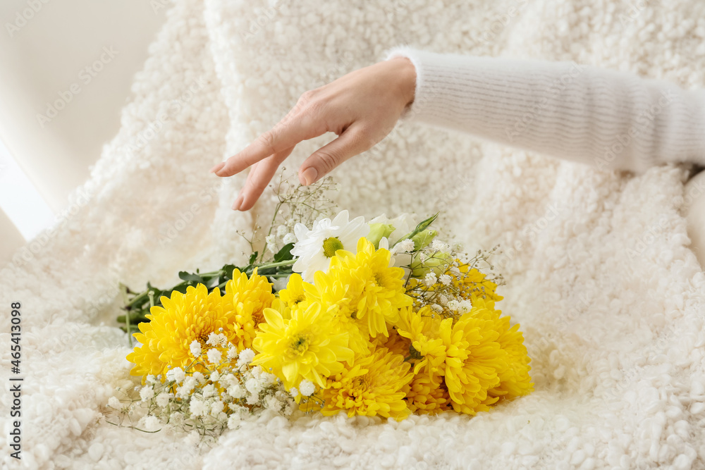 Female hand and bouquet of beautiful flowers on light background