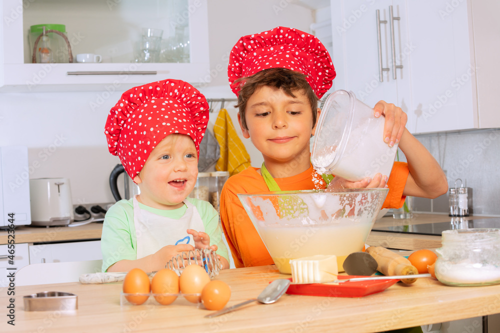 Child pour flour to the mix bowl cooking cookies