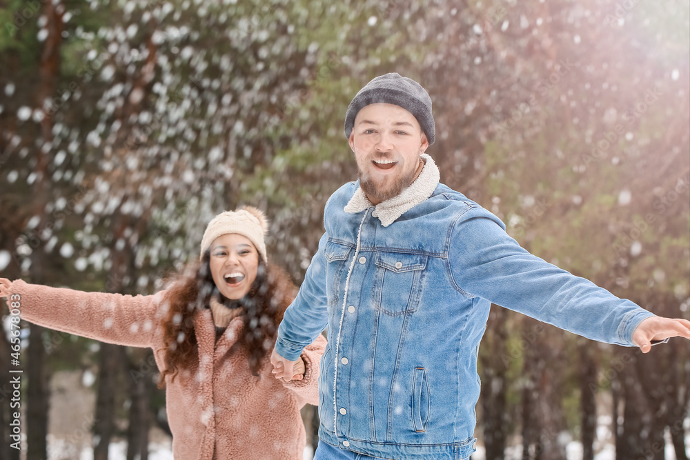 Happy young couple having fun in forest on winter day