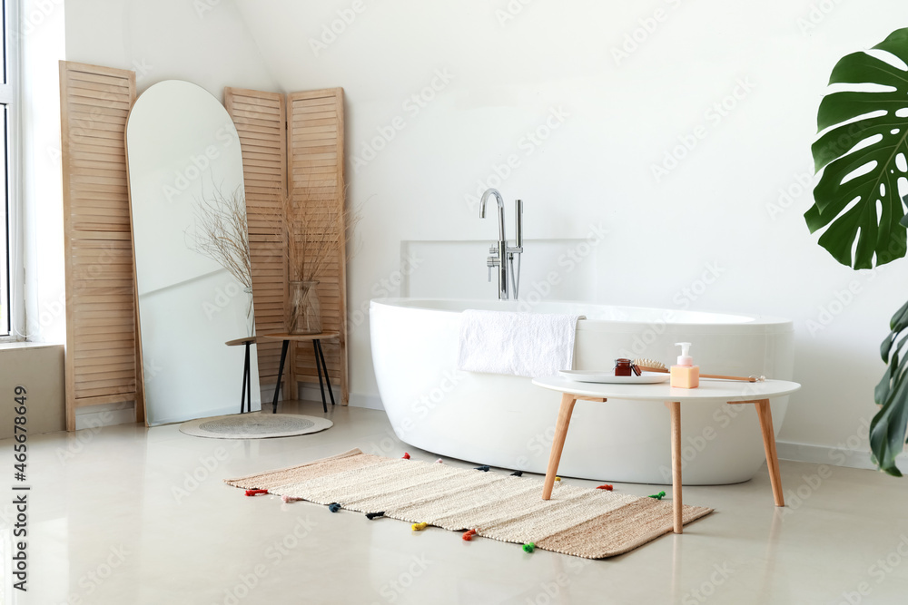 Interior of light room with mirror and bathtub