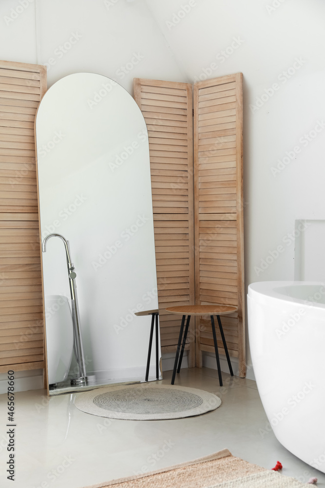 Mirror and table near folding screen in bathroom