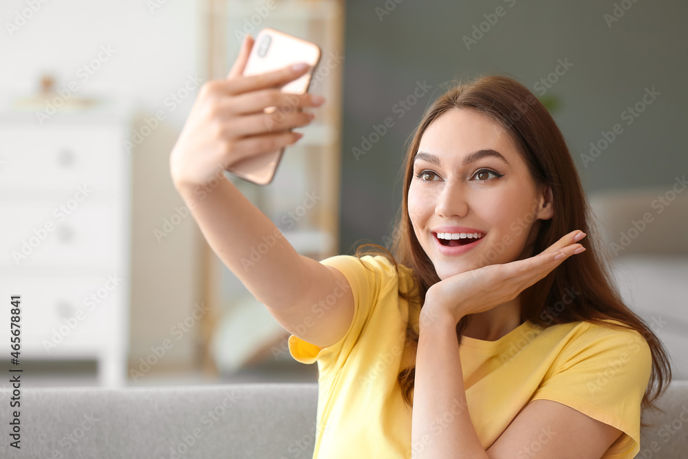 Pretty woman sitting on sofa and posing for selfie