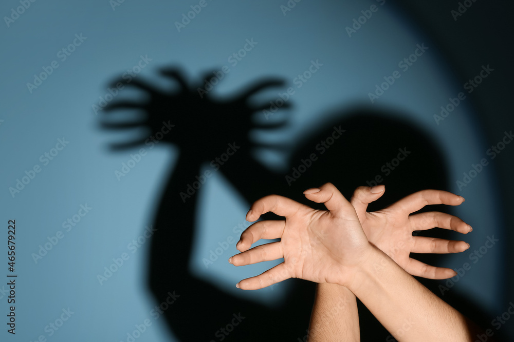 Woman making shadow spider with her hands on color background