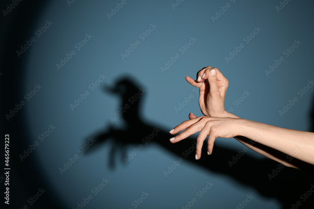 Woman performing a shadow play on color background