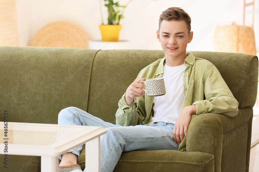 坐在家里沙发上喝着热茶的十几岁男孩