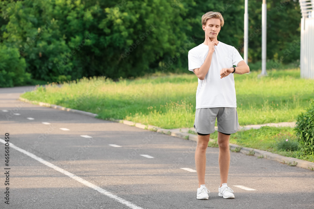 运动型男性跑步者在户外检查脉搏