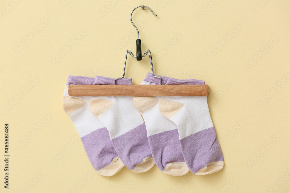 Hanger with stylish socks on color background