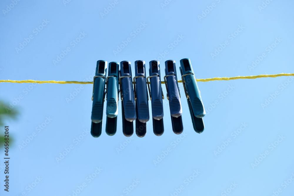 Plastic clothespins hanging on rope against blue sky