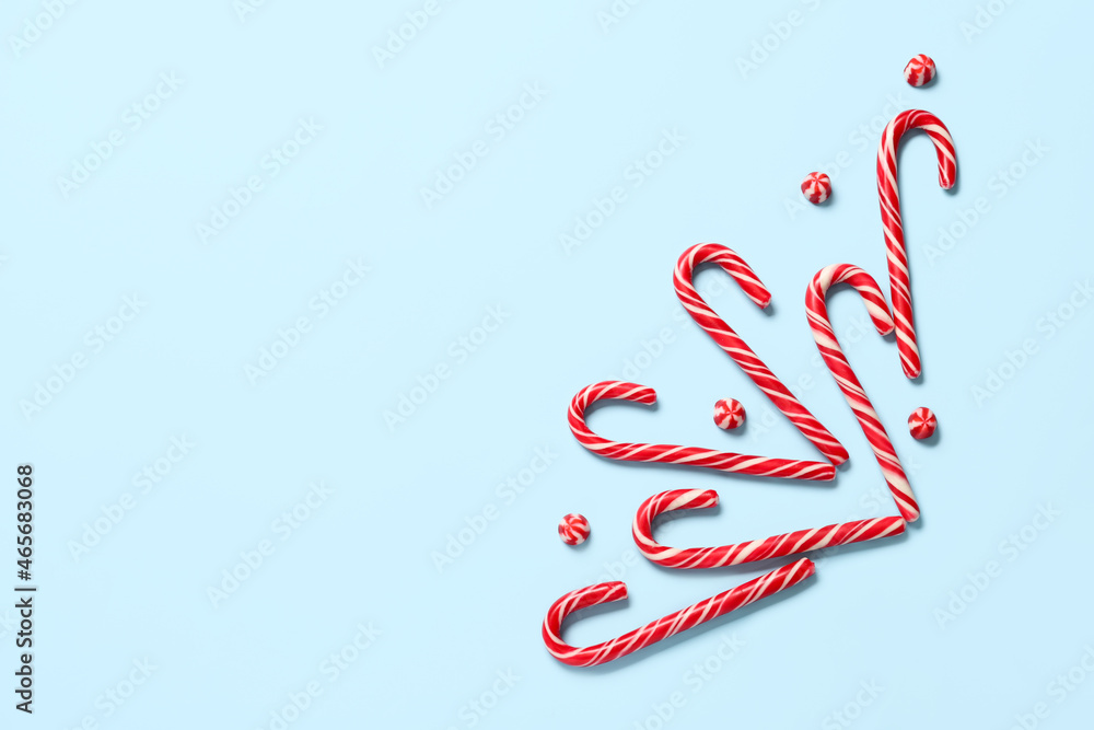 Sweet candy canes on color background