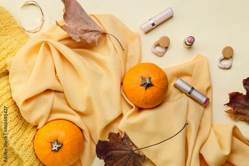 Stylish female accessories, cosmetics and autumn decor on light background