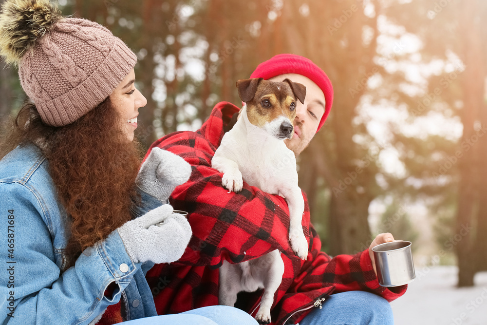 Happy young couple with dog in forest on winter day